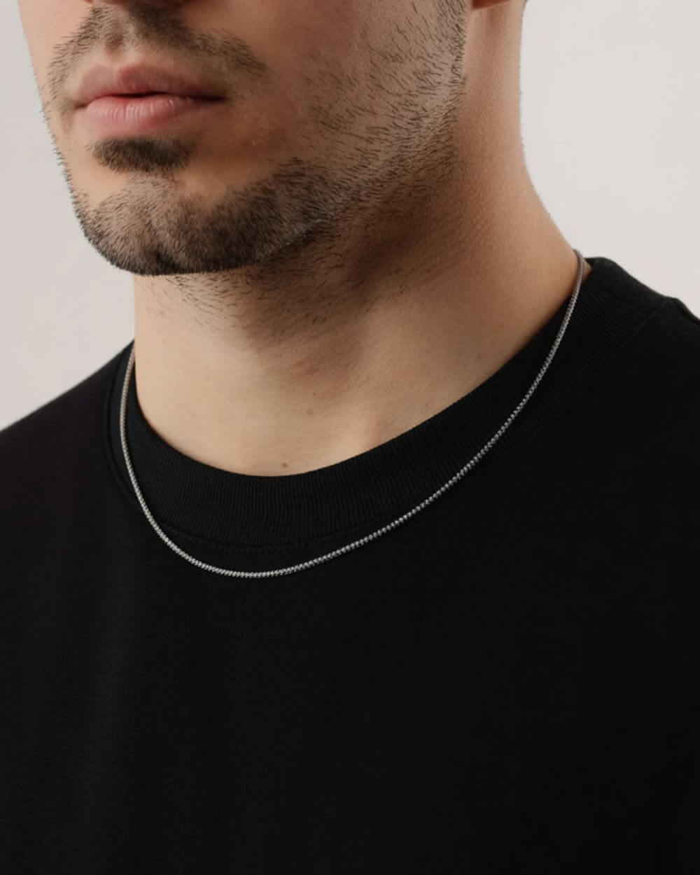 Box collectie sieraden: man met een stijlvolle stainless steel box ketting op een zwart shirt.