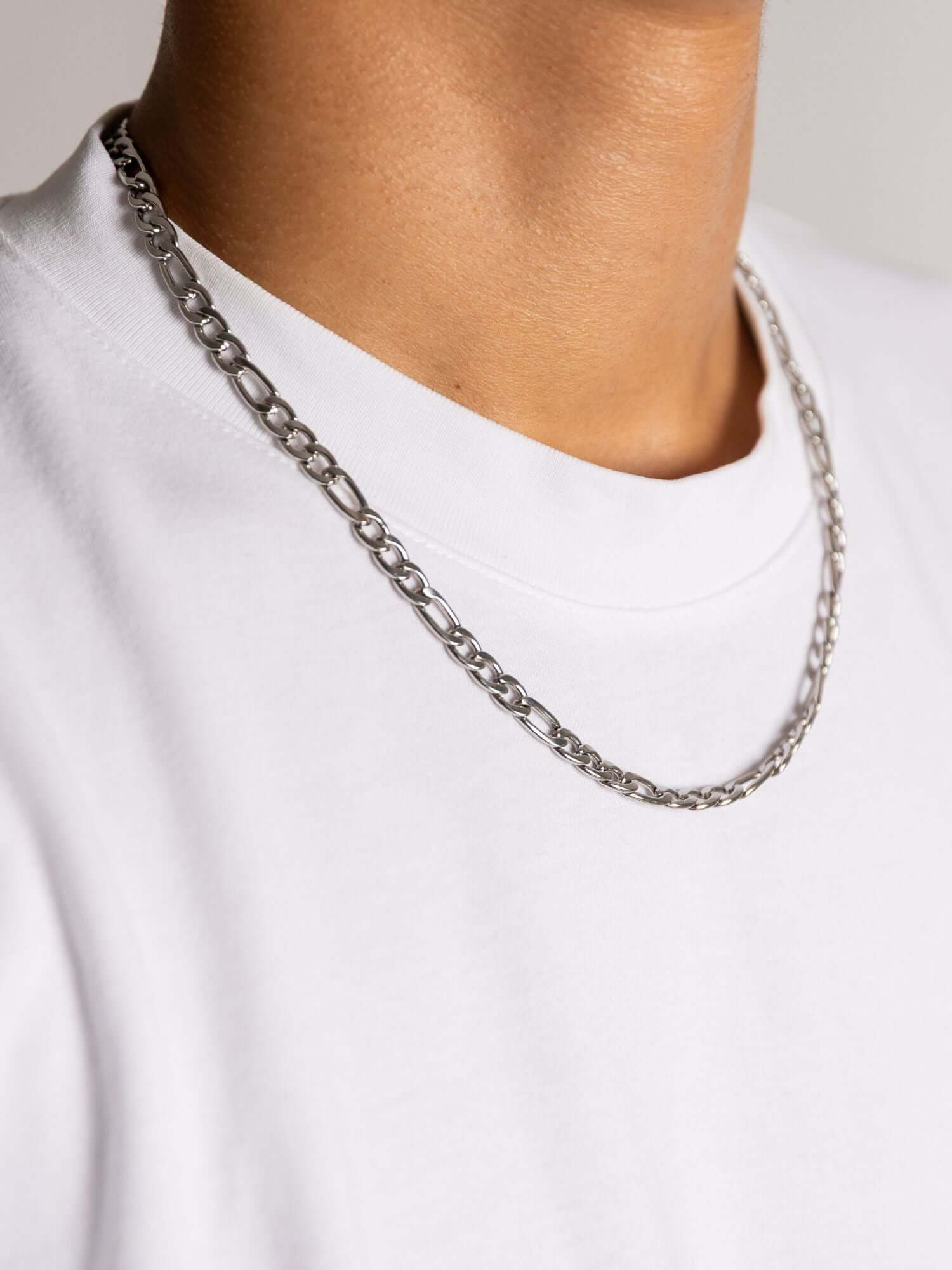 Zilveren figaro ketting in 3MM en 6MM, stijlvol gedragen op een witte T-shirt.
