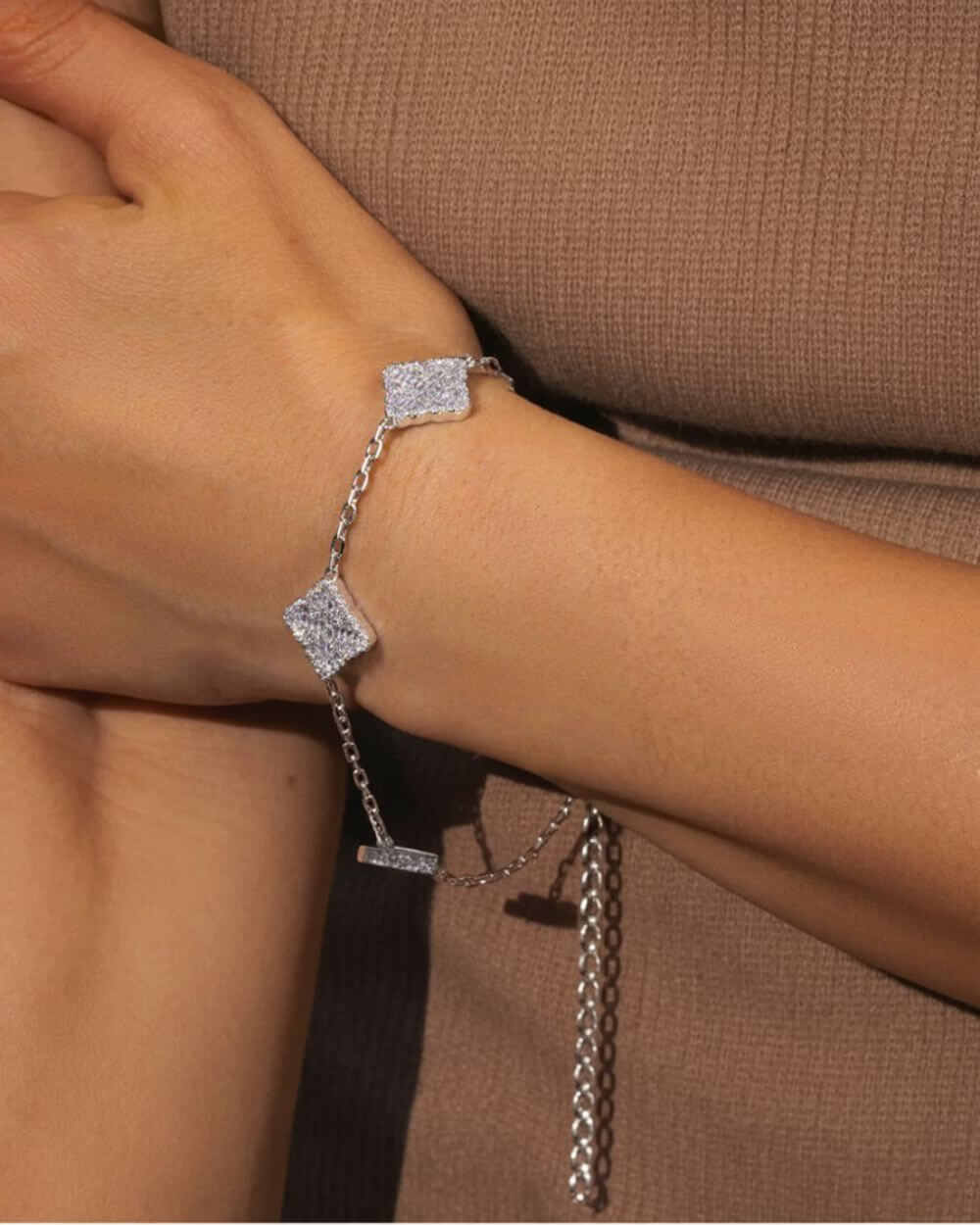 pulsera Clover plateada ICED OUT en la muñeca, con un diseño brillante y un estilo elegante.