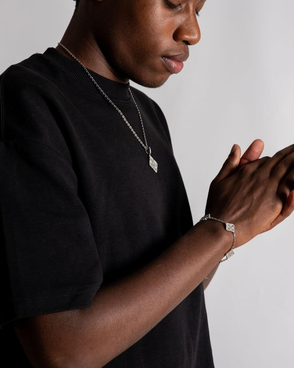 Clover hanger zilver worn by a person in black shirt, showcasing luxury jewelry with an iced out design.