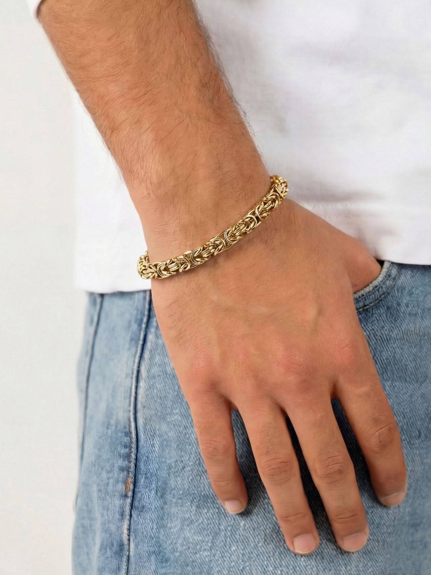 Gouden Byzantijnse konings armband 6MM gedragen om een pols met een casual outfit.