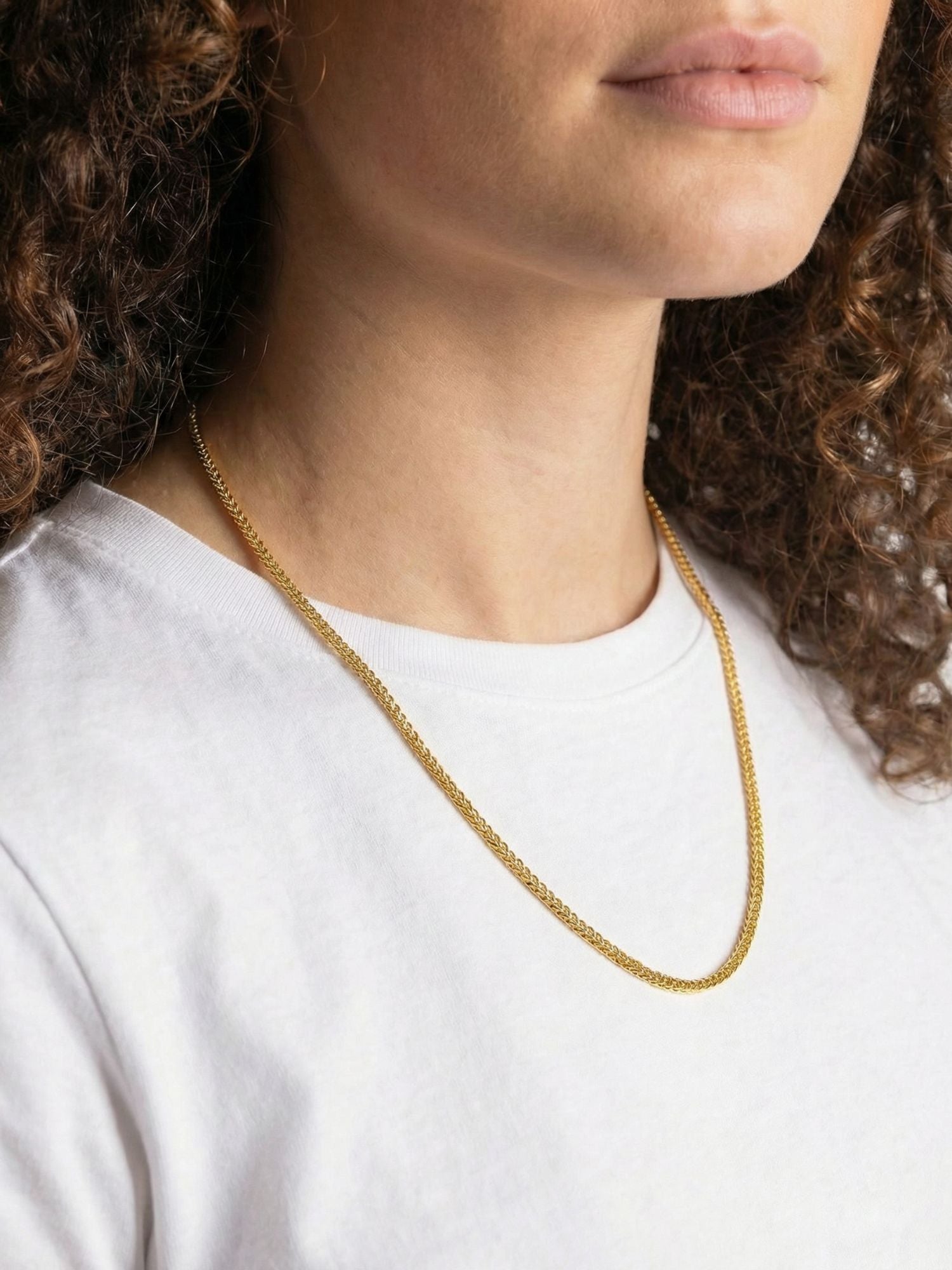 Gouden Franco Vossenstaart Ketting 3MM gedragen door een vrouw met krullend haar op een witte T-shirt.