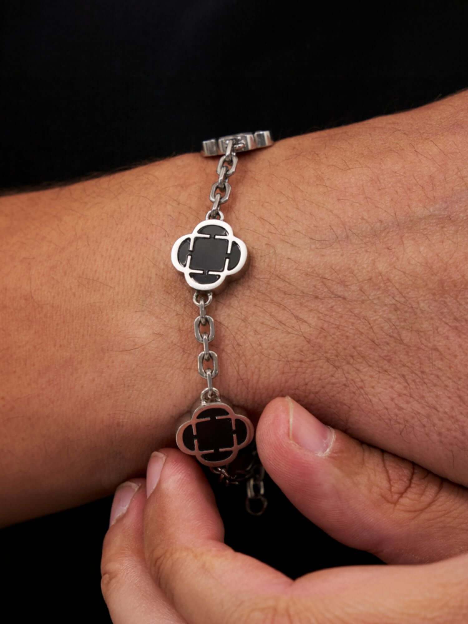 Zilveren Klaver Armband Zwart Onyx Steen op een hand met een zwart en zilver ontwerp.