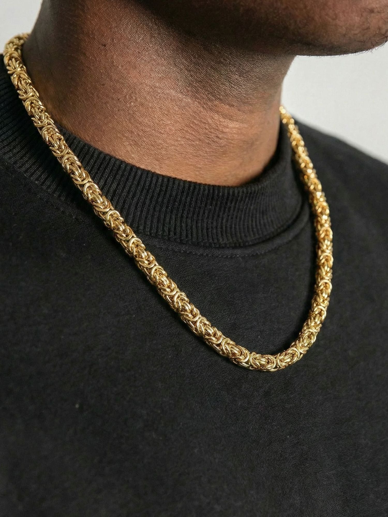 Gouden Byzantijnse Konings Ketting 6MM gedragen door een man, toont het iconische vlechtpatroon in luxe goud.
