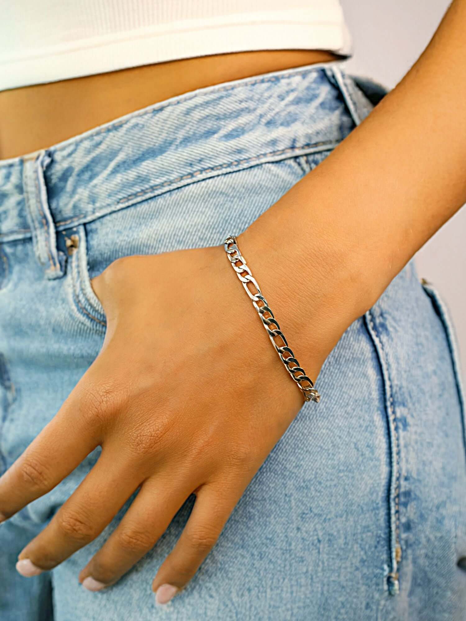 Zilveren Figaro Armband 3MM & 5MM gedragen op een hand met casual outfit in lichte spijkerbroek.
