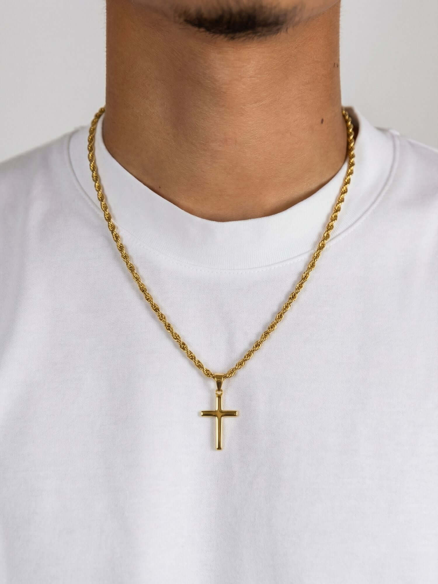 Pendente a croce dorato di lusso indossato su una camicia bianca con catena d'oro