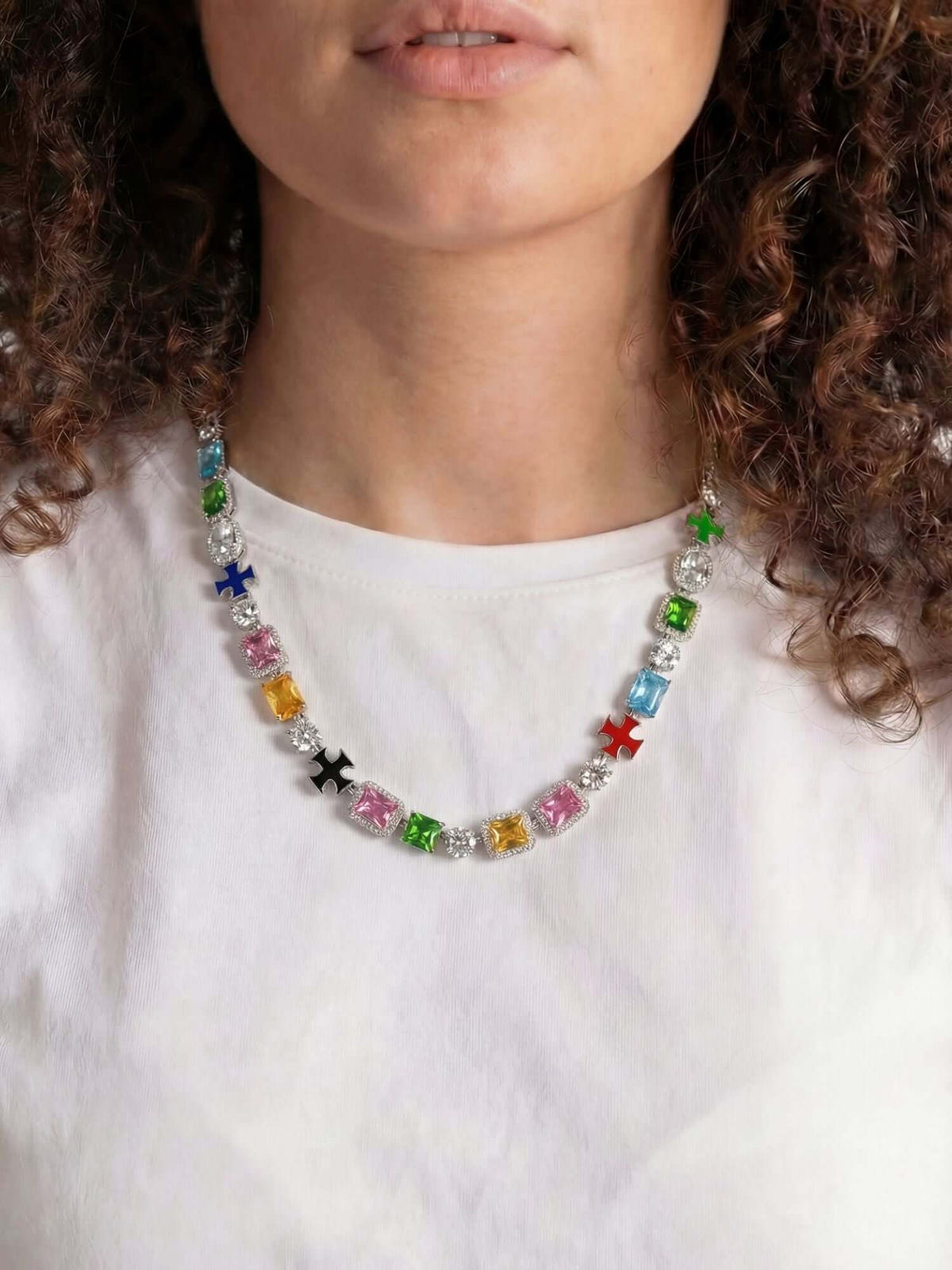 Kruis en edelstenen ketting ICED OUT in witgoud met kleurrijke edelstenen, elegant gedragen door model.