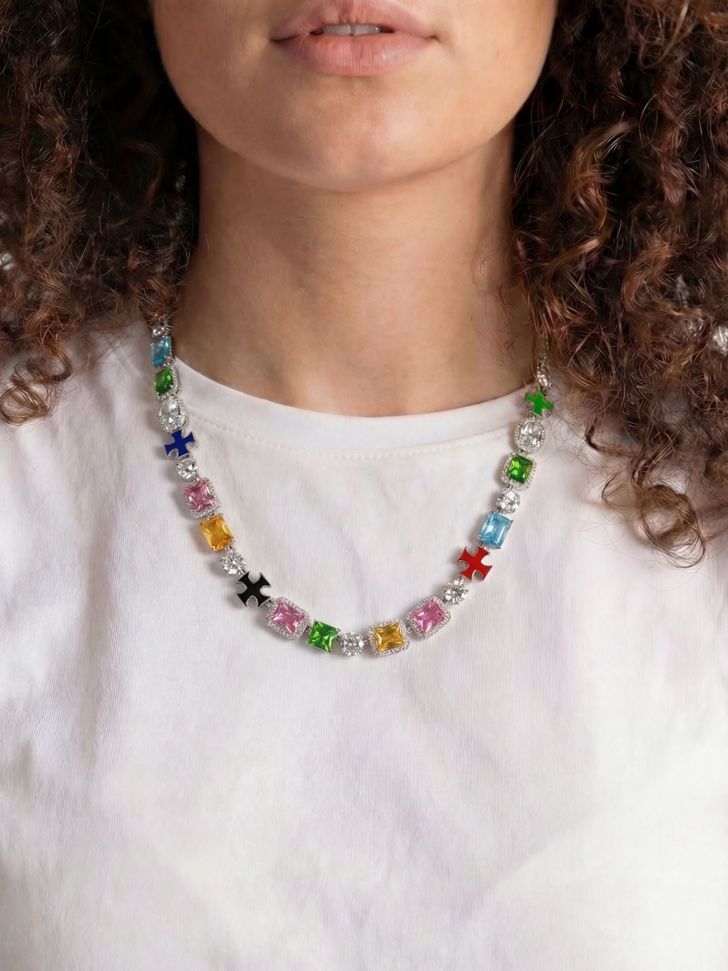 Cross and gemstone necklace ICED OUT in white gold with colorful gemstones, elegantly worn by a model.