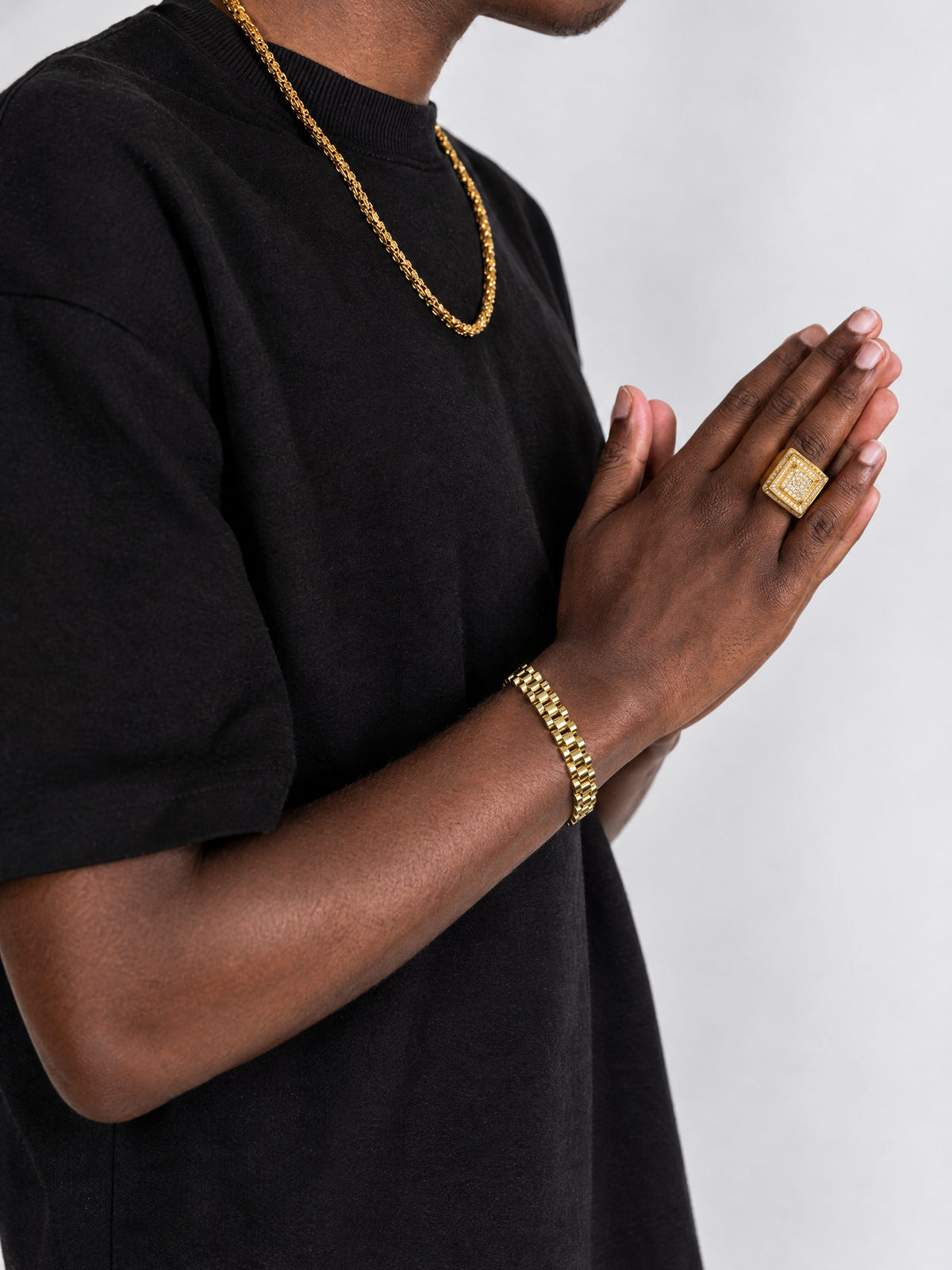 Brazalete jubilee dorado combinado con una cadena y un anillo dorados sobre una camiseta negra