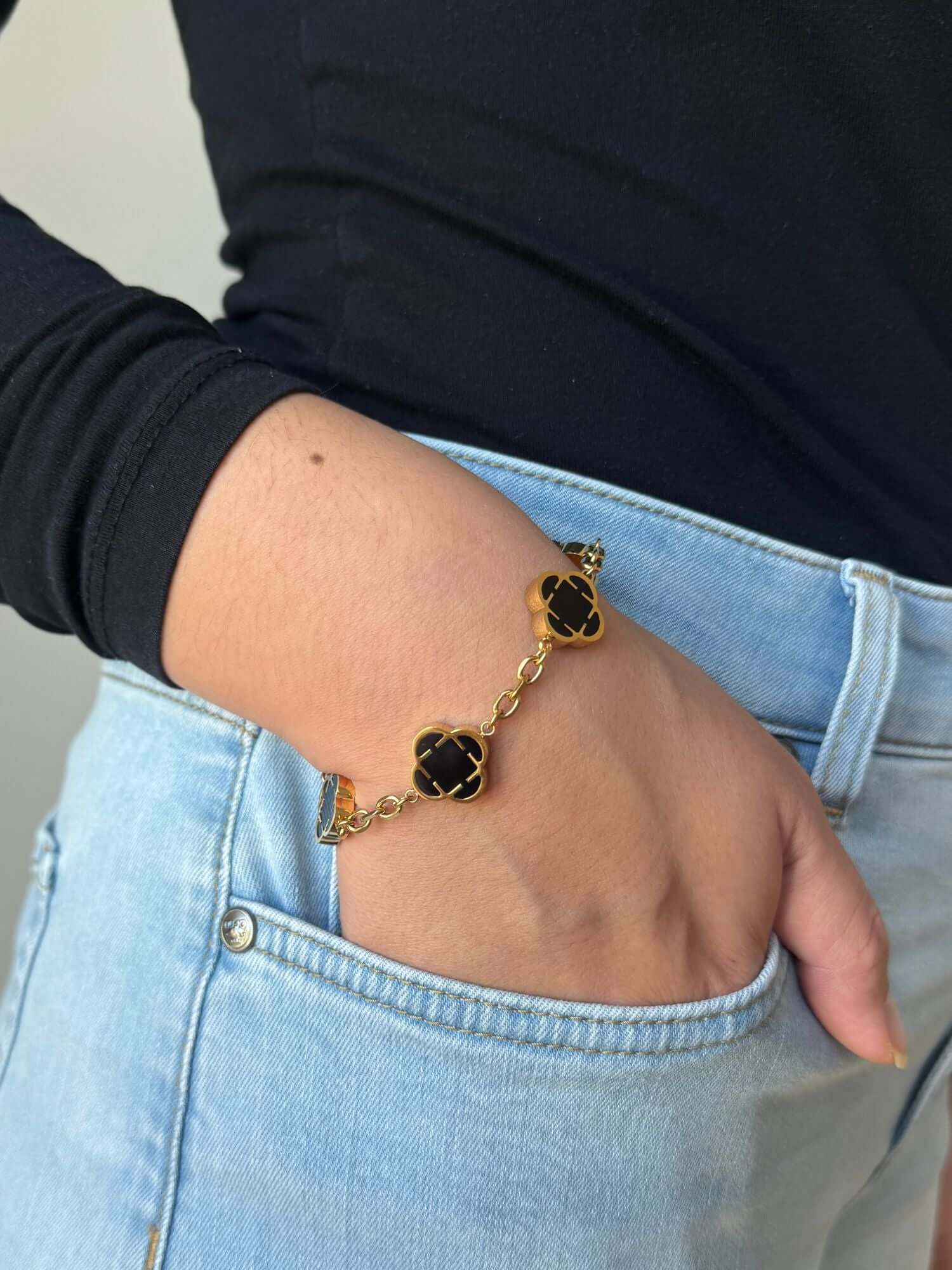 Klaver Gouden Armband Zwart Onyx Steen gedragen om een arm, met drie zwarte onyx klavers in een gouden setting.