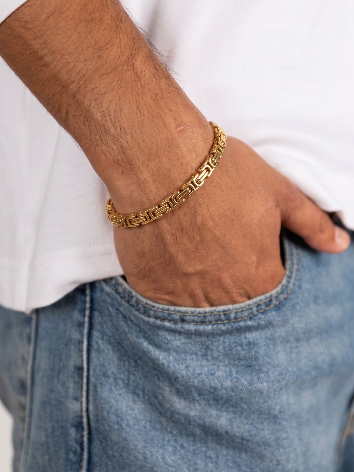 Königsarmband Edelstahl goldfarben 5 mm, zu weißem T-Shirt und Jeans getragen, Hand in der Tasche