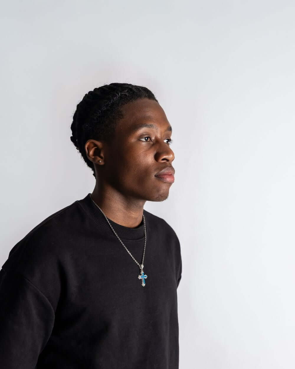 Man wearing a Blauwe Kruis Hanger Zilver ICED OUT against a plain background, highlighting the jewelry's design.