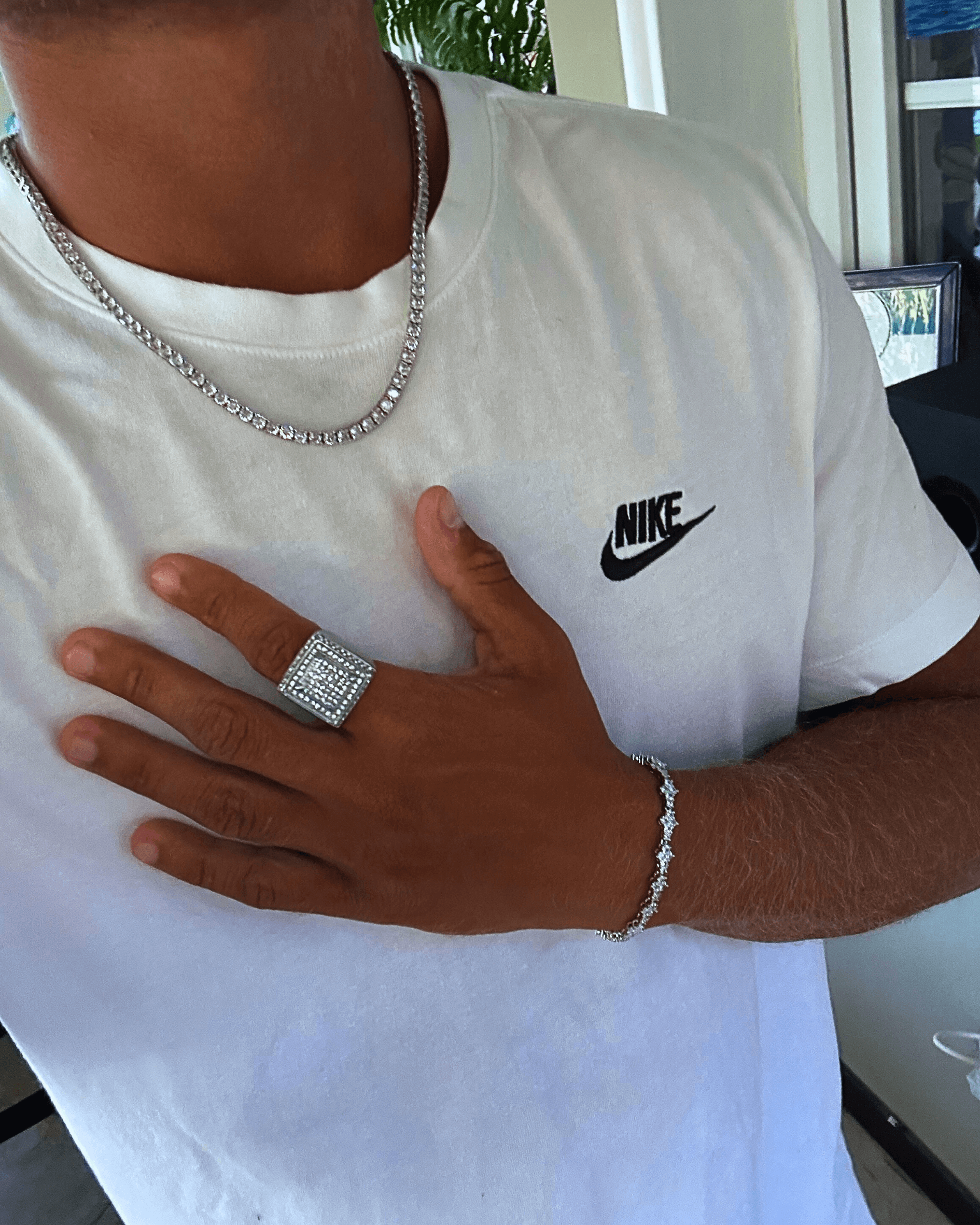 Stylish man wearing a box ring zilver, silver chain, and bracelet with a Nike shirt.