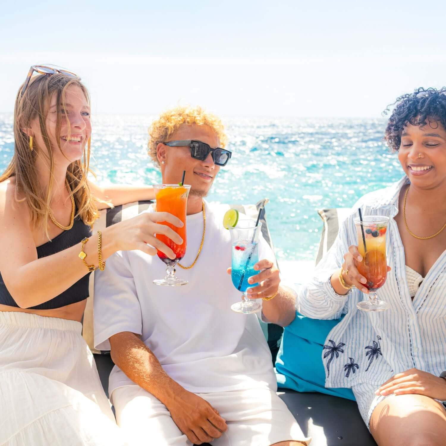 Vrienden op een boot aan zee genieten van kleurrijke cocktails in de zon