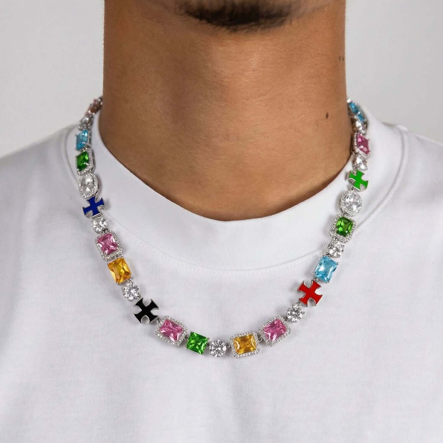 Close-up van kleurrijke edelstenen ketting met kruisbedels gedragen om de hals op wit T-shirt