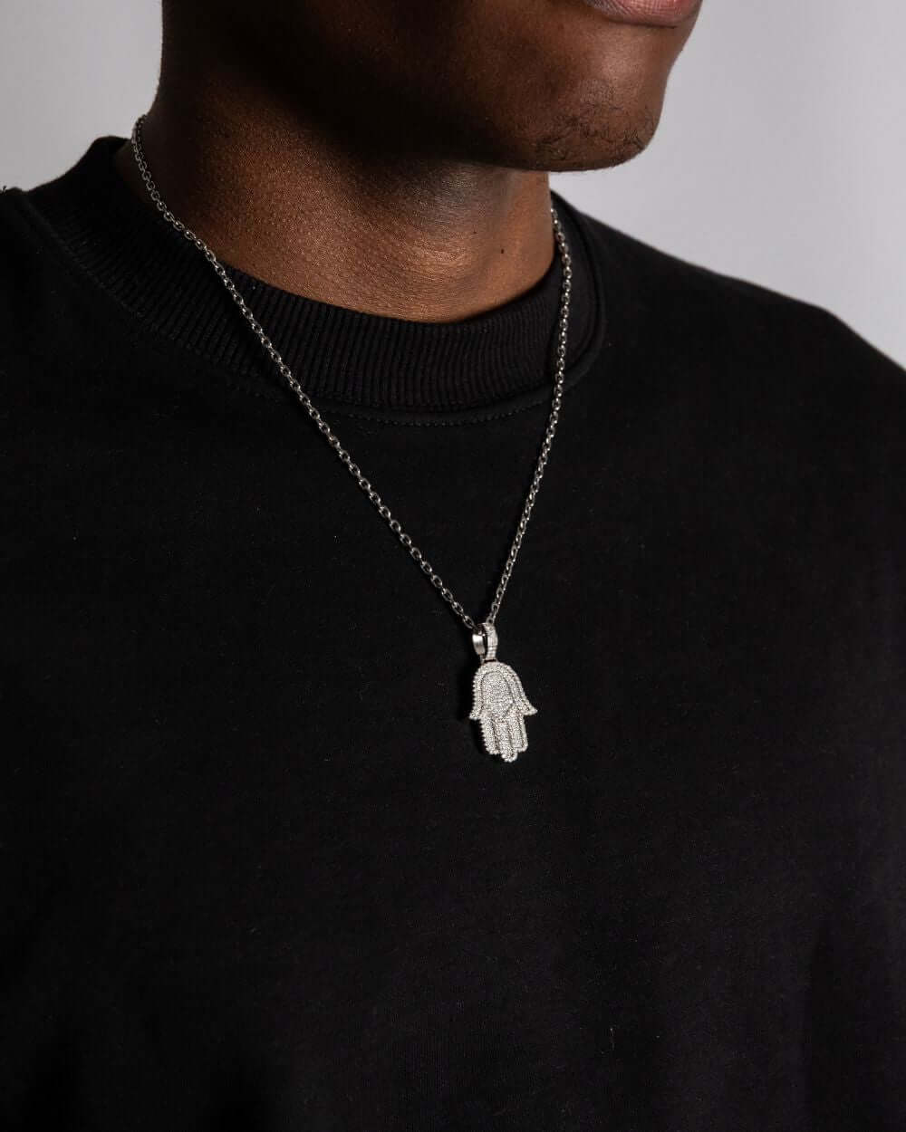 Hamsa hanger moissanite worn on a silver chain, showcasing its unique iced out design.