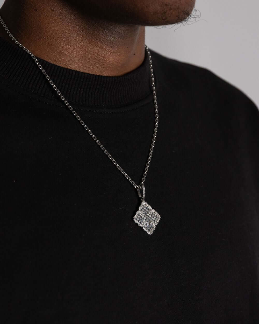 Clover hanger zilver worn as a stylish necklace pendant, showcasing its sparkling design against a black sweatshirt.