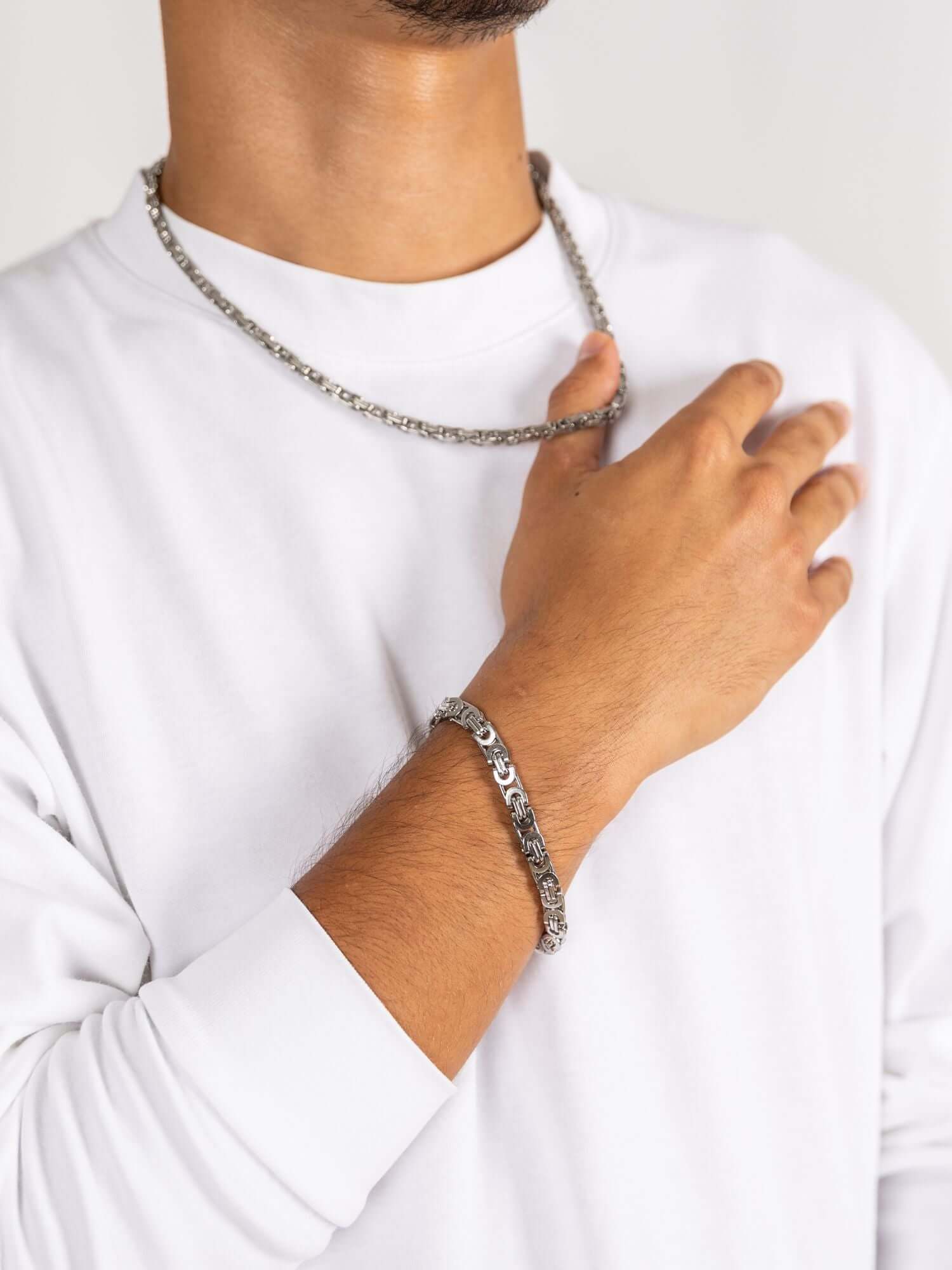 Man wearing a konings schakel armband zilver and a matching chain, showcasing a stylish silver accessory.