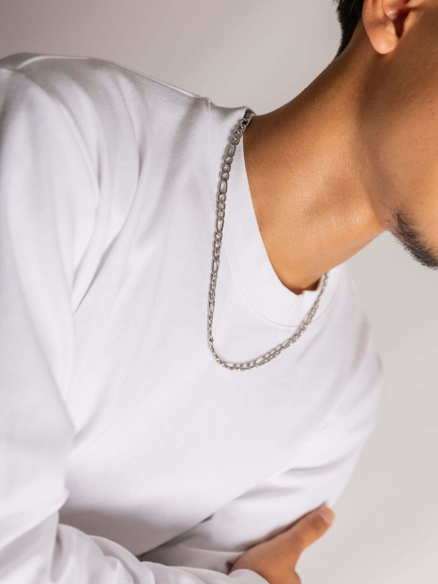 Zilveren figaro ketting, model draagt het met een wit shirt voor een stijlvolle uitstraling.