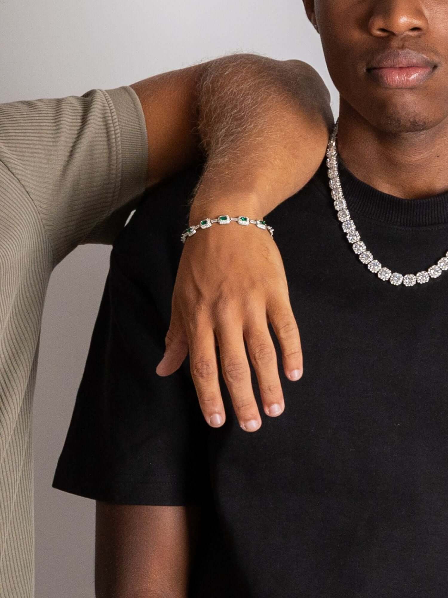 Emerald armband showcased on a model's wrist, complemented by a diamond necklace and stylish attire.