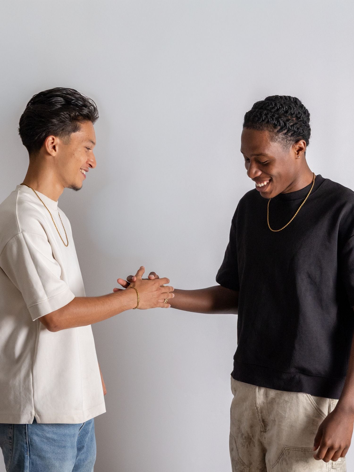 Twee mannen die elkaar de hand schudden, terwijl ze gouden rope kettingen dragen, op een neutrale achtergrond.