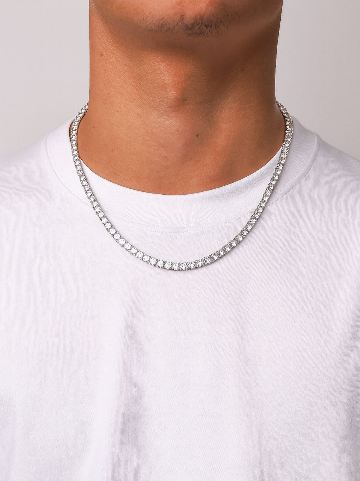 Zilveren tennis ketting van Carpe Ice gedragen door man in witte T-shirt, met luxe diamanten uitstraling.