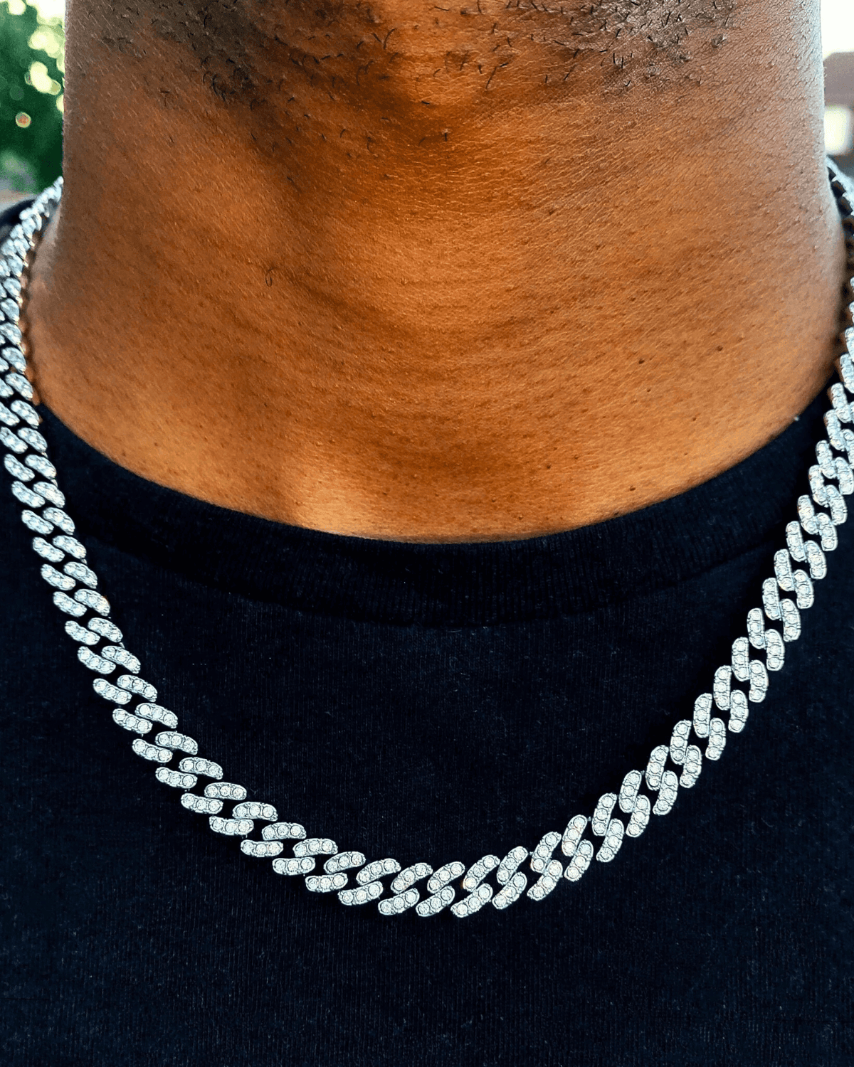 Close-up of a sparkling diamond chain necklace worn by a person with dark skin tone, highlighting jewelry fashion trends.