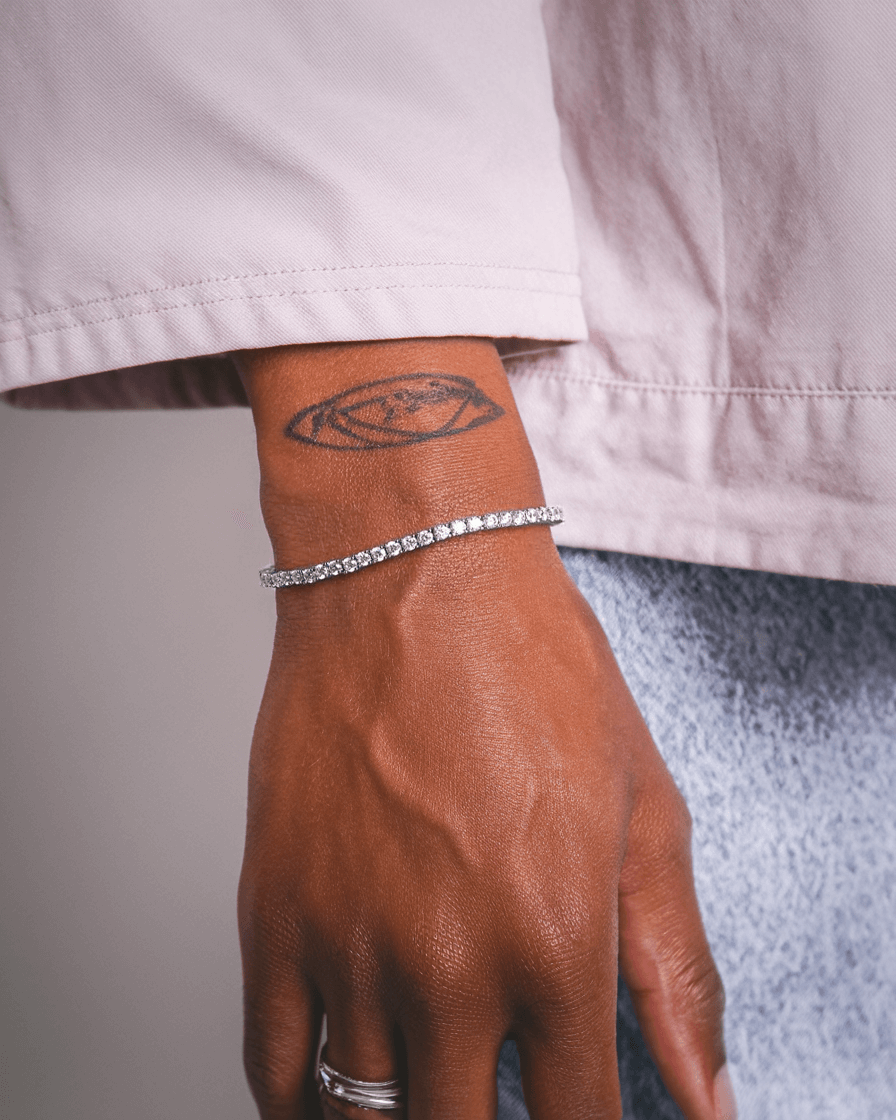 Zilveren tennis armband 3MM en 5MM gedragen door een persoon met een tattoo op de arm.