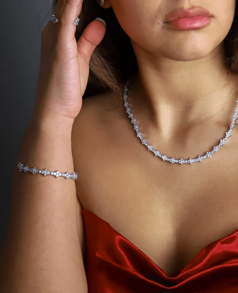 Model showcasing sparkling jewelry necklace and bracelet, wearing elegant red dress.
