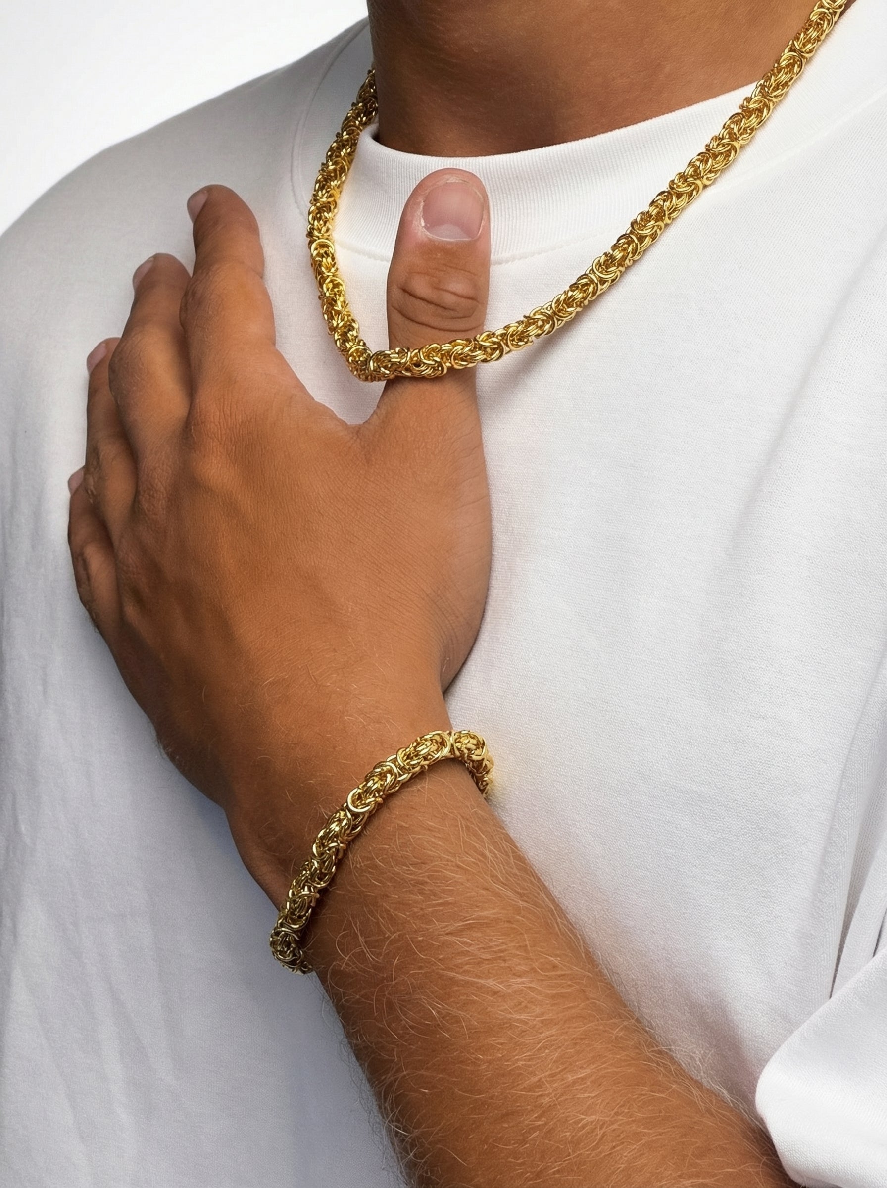 Man die de Gouden Byzantijnse Konings Ketting 6MM en armband draagt, stijlvol en elegant in een witte T-shirt.