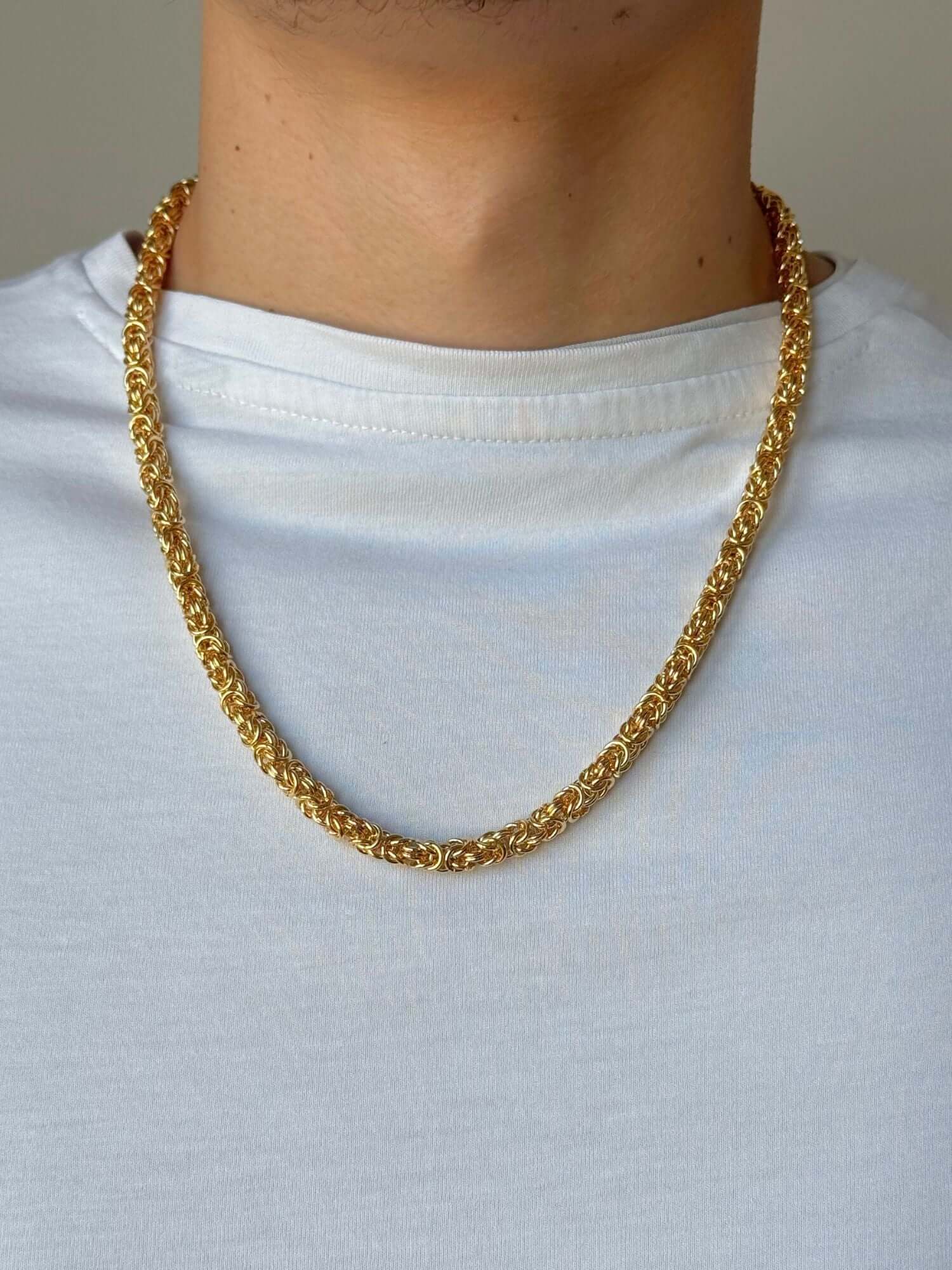 byzantijnse gouden ketting gedragen door een man met een witte T-shirt.
