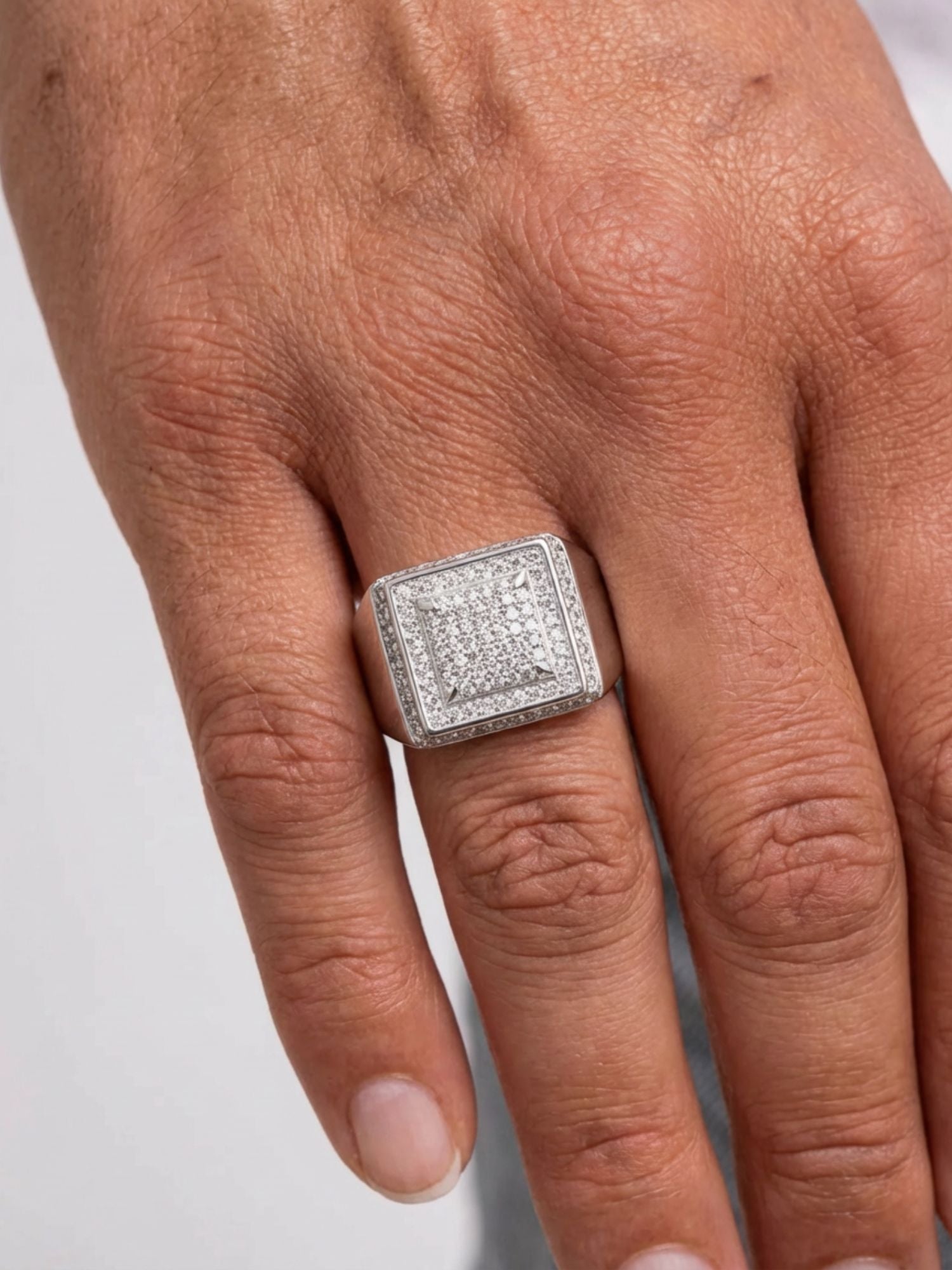 Main portant une bague Box ICED OUT en argent avec de superbes diamants synthétiques, mettant en valeur son design luxueux.