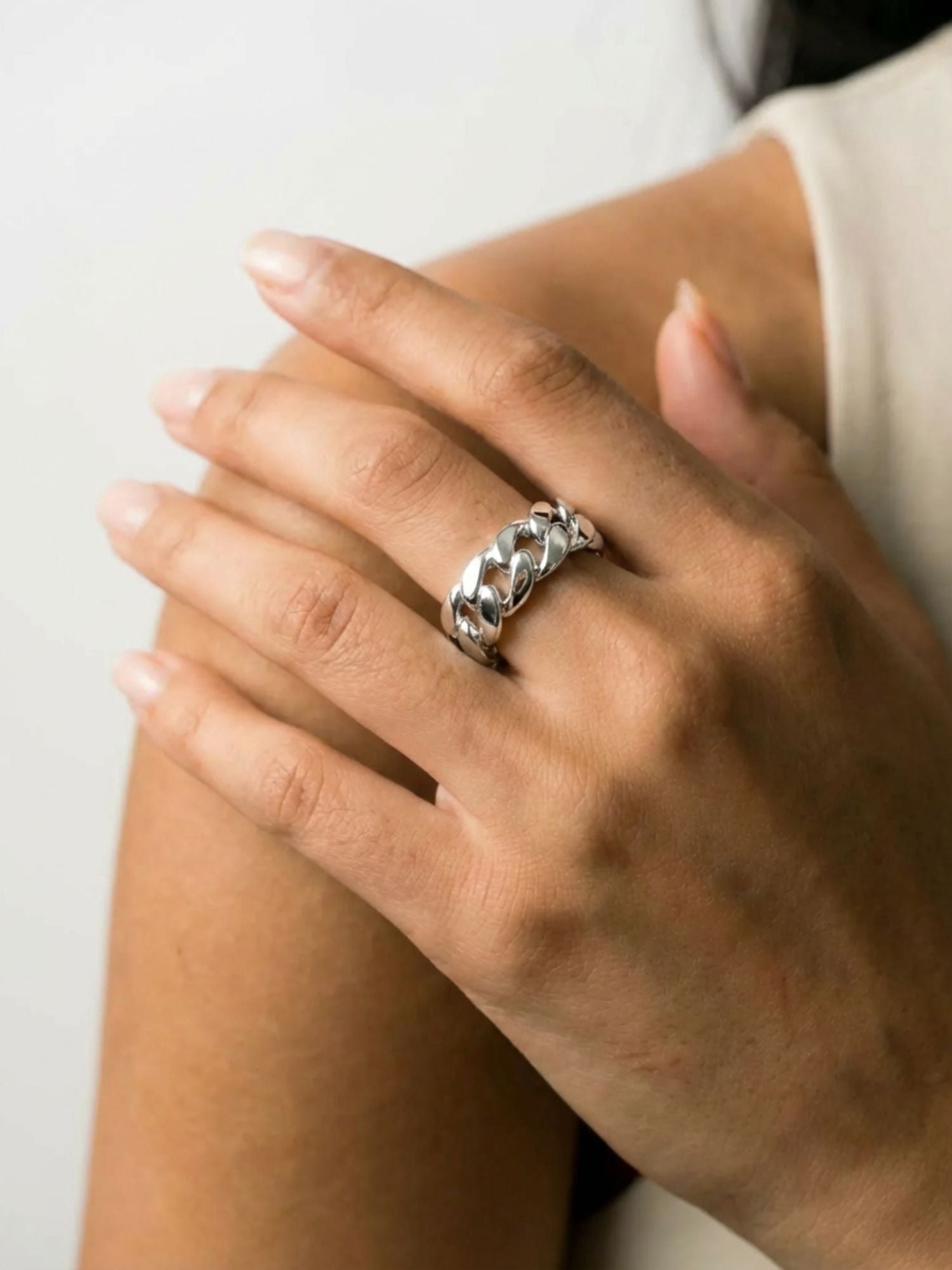 Close-up van Carpe Ice zilveren Cuban schakel ring met glanzende afwerking en gedetailleerd link design op een hand