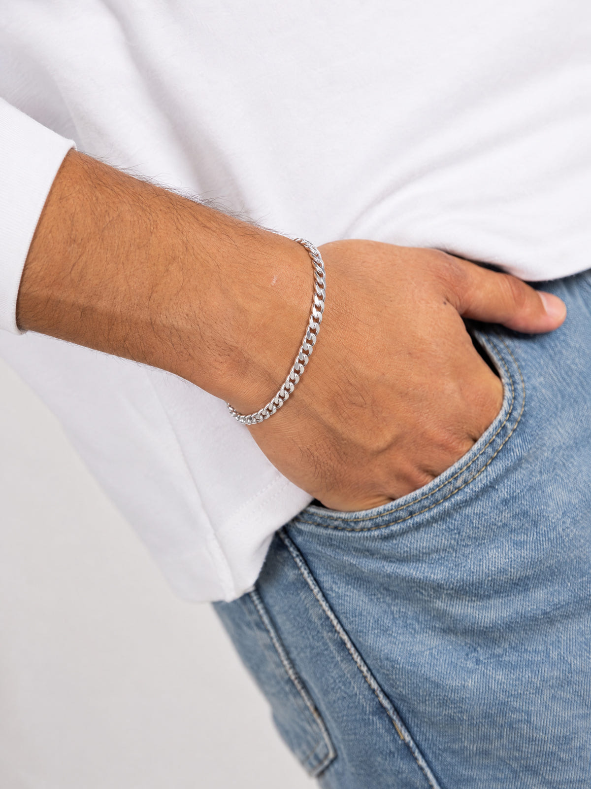 Cuban armband 925 sterling zilver 4 mm om de pols van een man in wit shirt, hand in de broekzak.