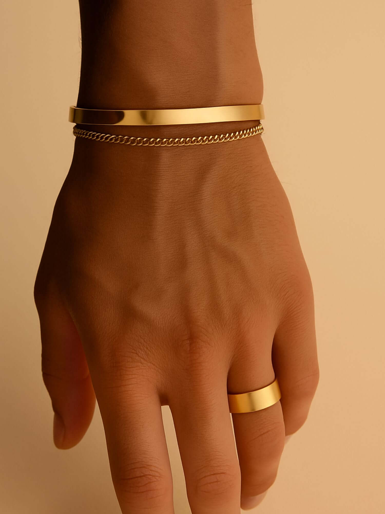 Gouden cuff armband 3MM en 5MM op een hand, gecombineerd met een gouden ring en ketting.