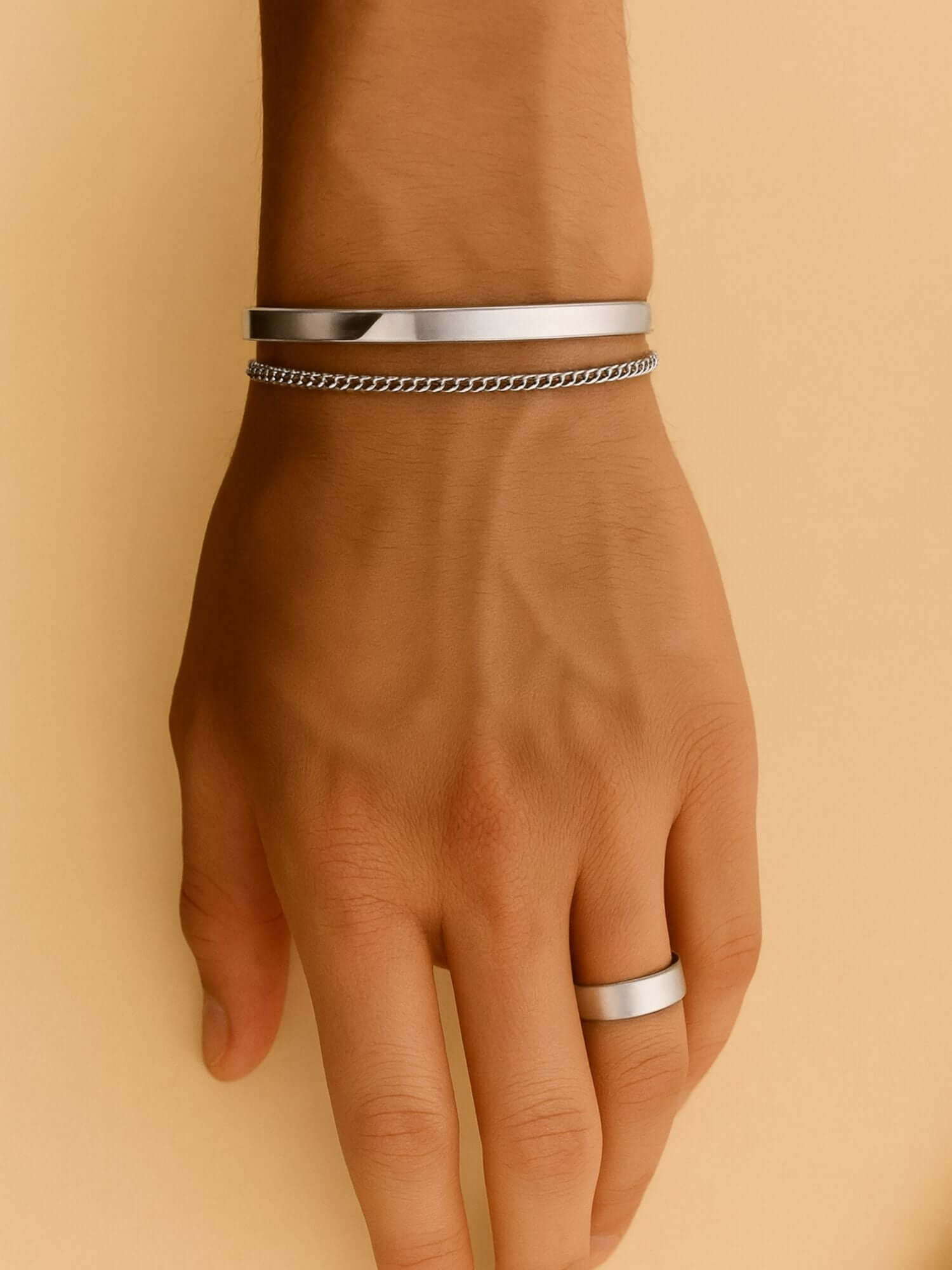 Zilveren cuff armband 3MM en 5MM op een hand, minimalistisch design met luxe uitstraling.