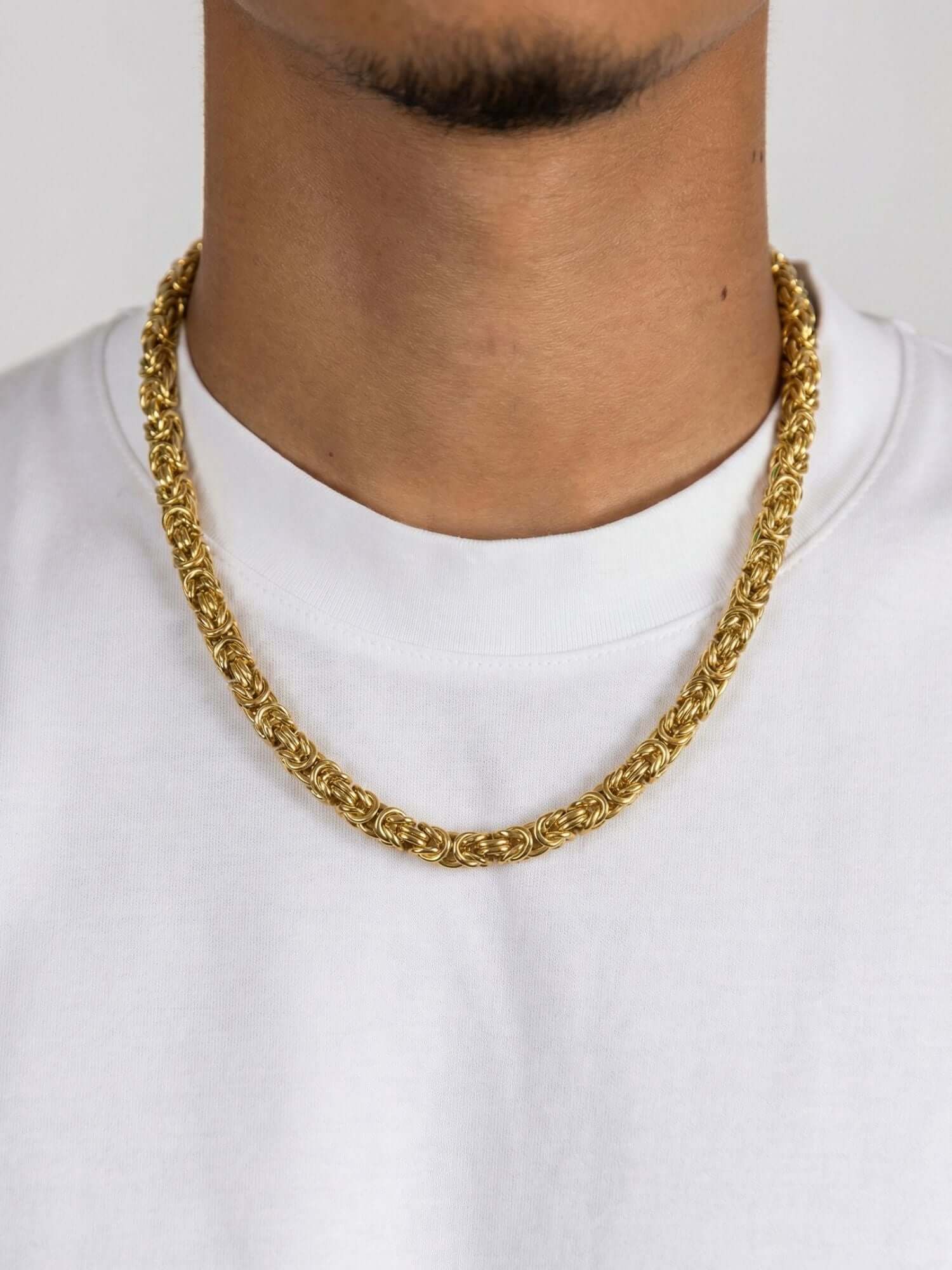 Gouden Byzantijnse Konings Ketting 6MM draperend over een witte trui, met een luxe en stijlvol ontwerp.