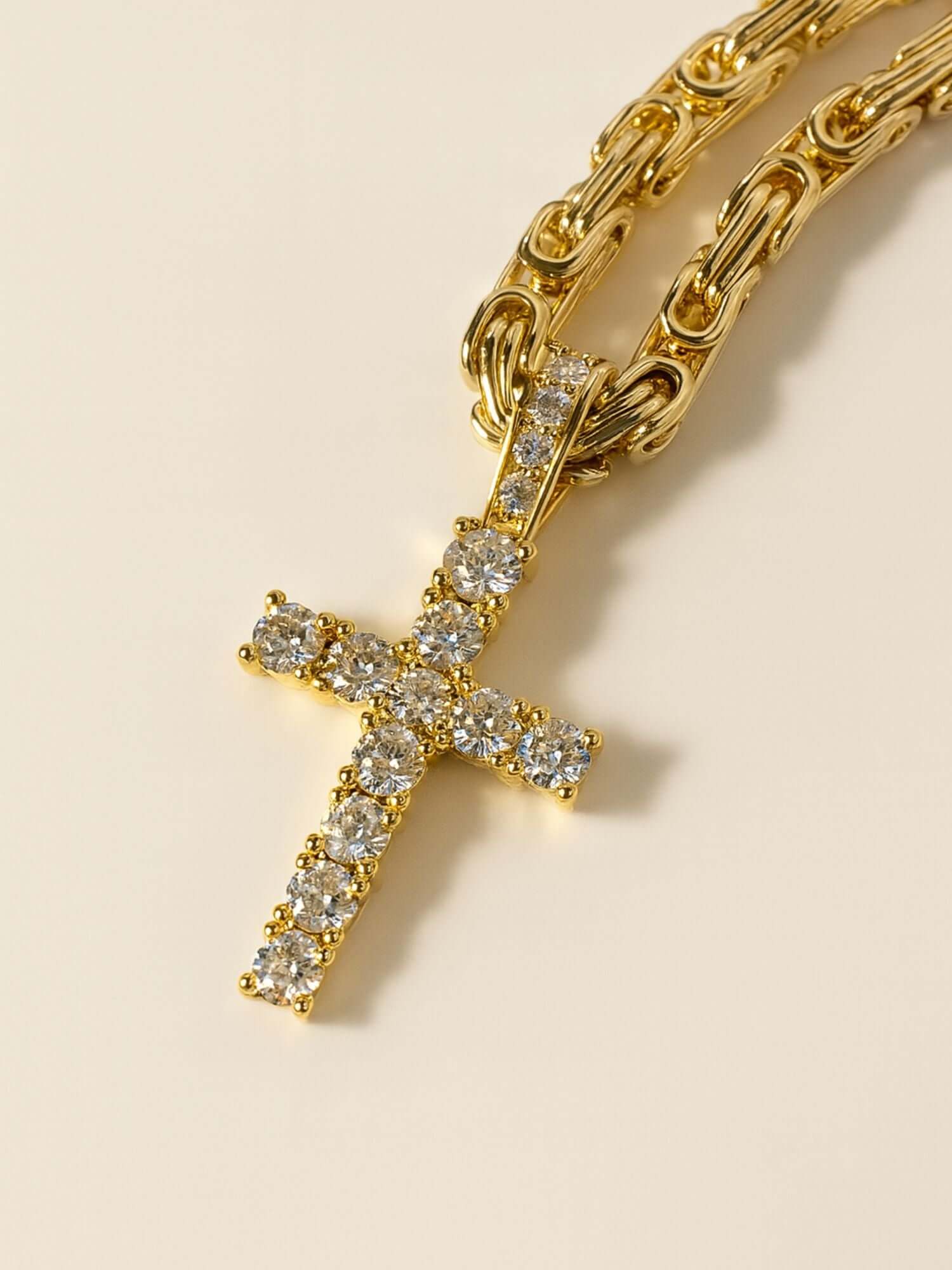 Ciondolo a croce dorato ICED OUT con scintillanti pietre VVS CZ su una collana a catena dorata.
