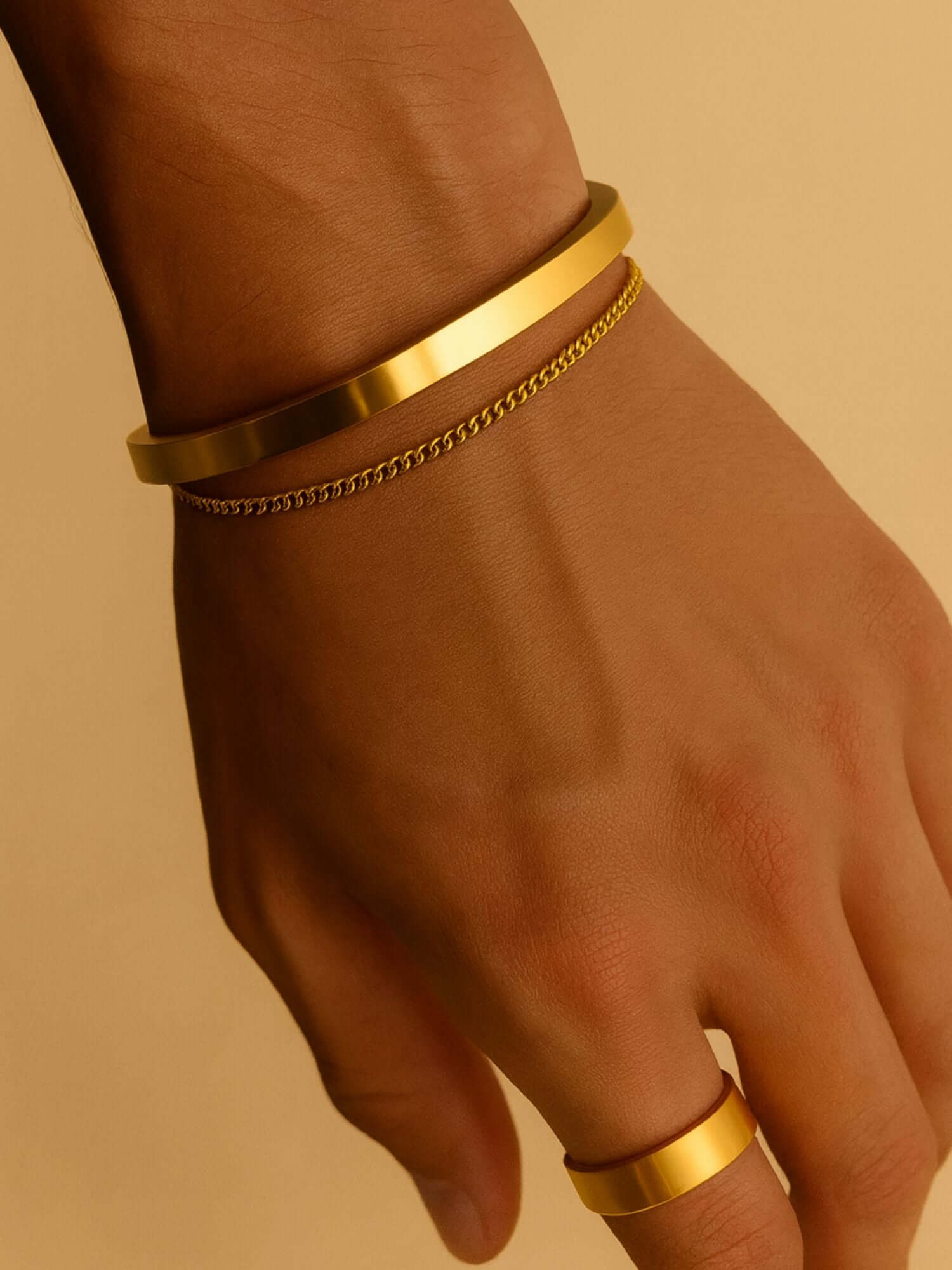 Gouden cuff armband 3MM en 5MM op een hand met een luxe uitstraling.