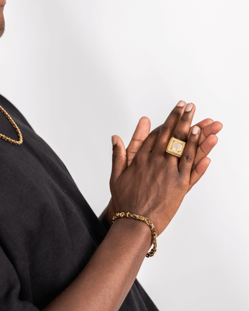 Ice Blox Ring in oro indossato da una persona, dal design audace, abbinato a un bracciale d'oro.