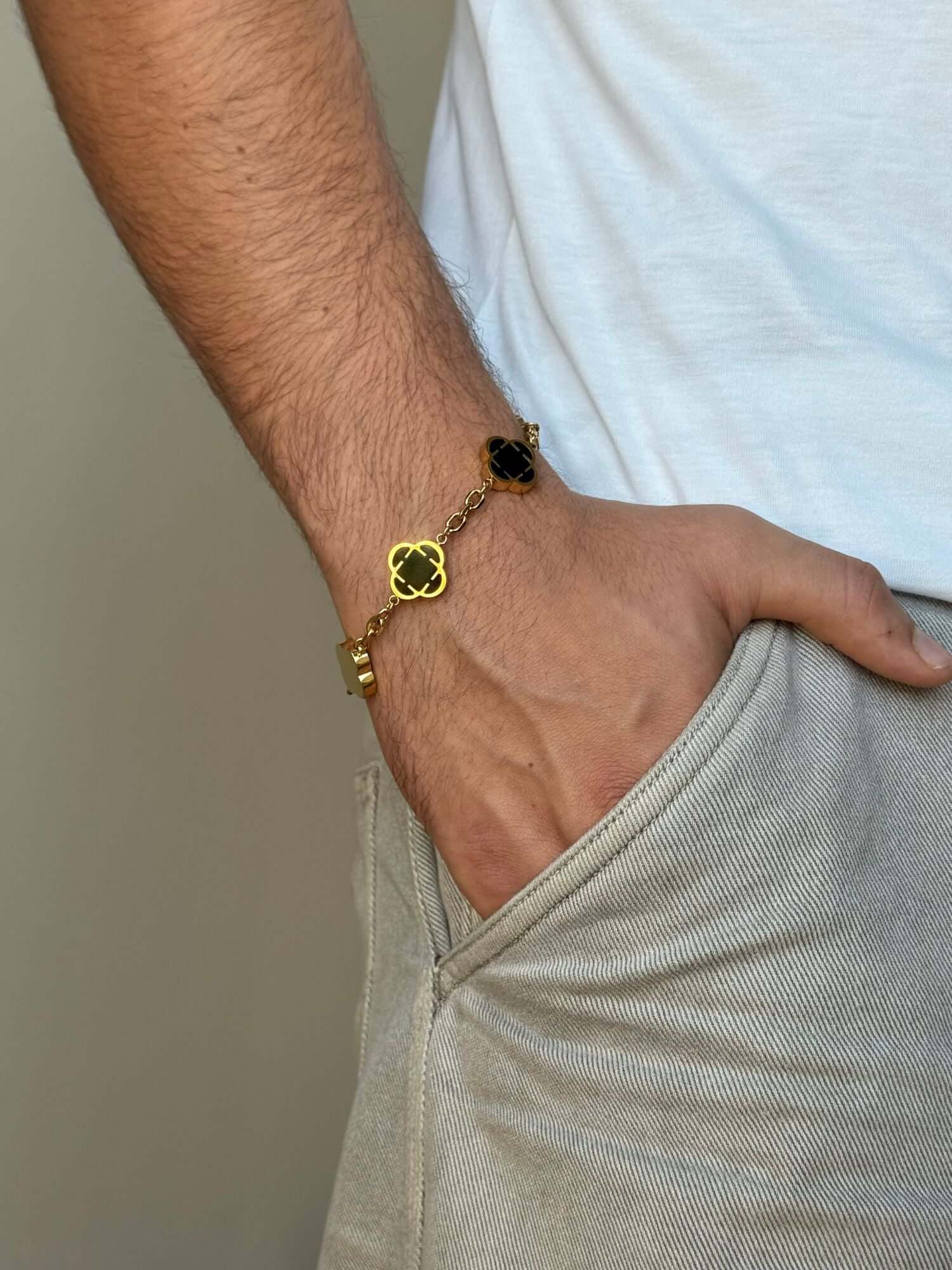 Bracciale a trifoglio in oro con pietra di onice nera, indossato al polso, bracciale con quadrifoglio dorato e pietra di onice nera