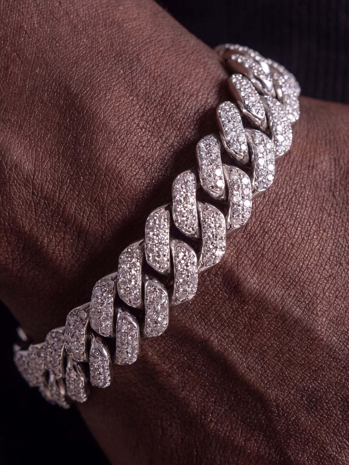 Pulsera cubana de moissanita iced out de 12 mm en plata de ley 925 maciza sobre una mano.