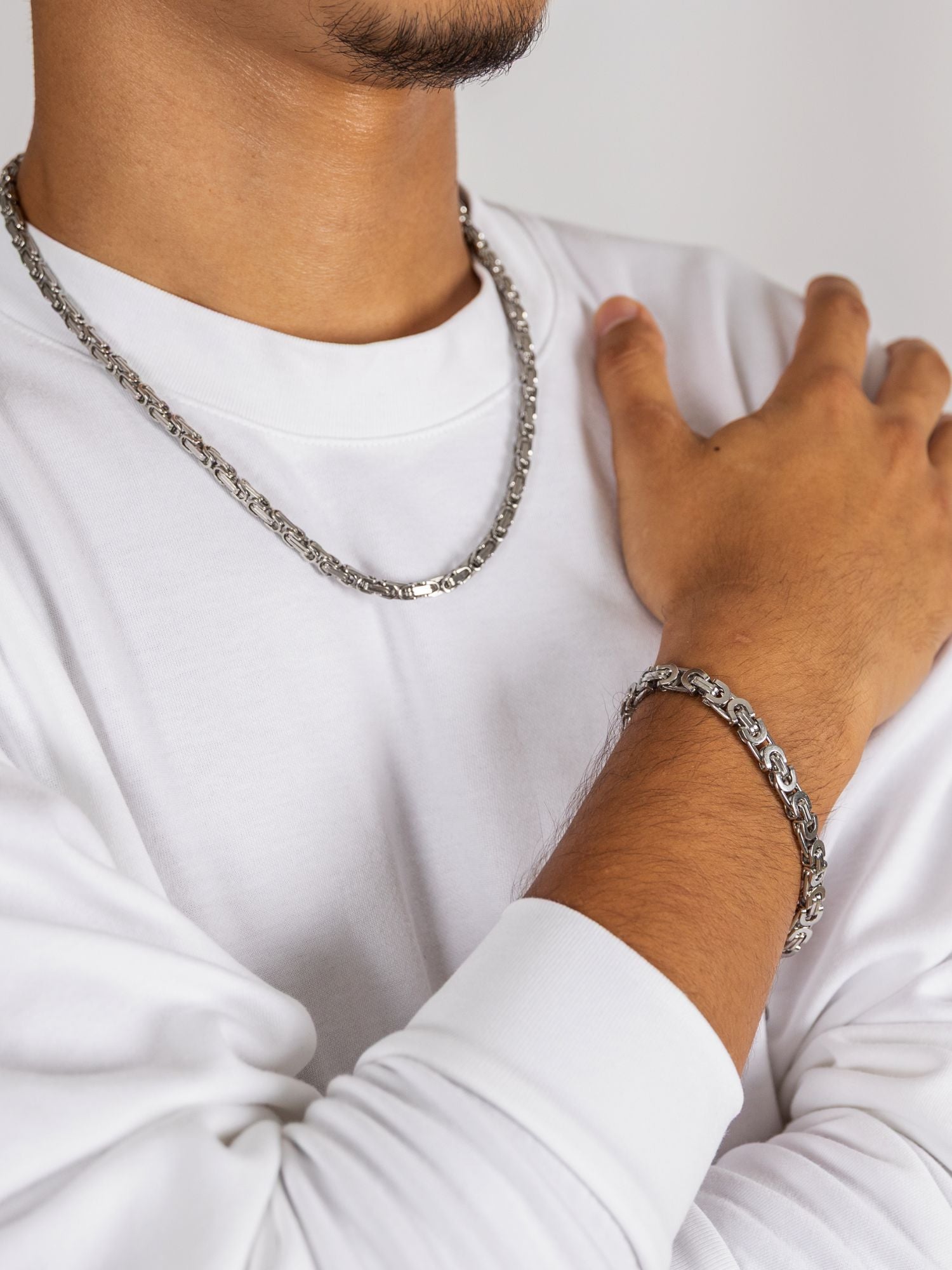 Man wearing a Zilveren Konings Schakel Ketting 5MM and bracelet, showcasing elegant silver jewelry.