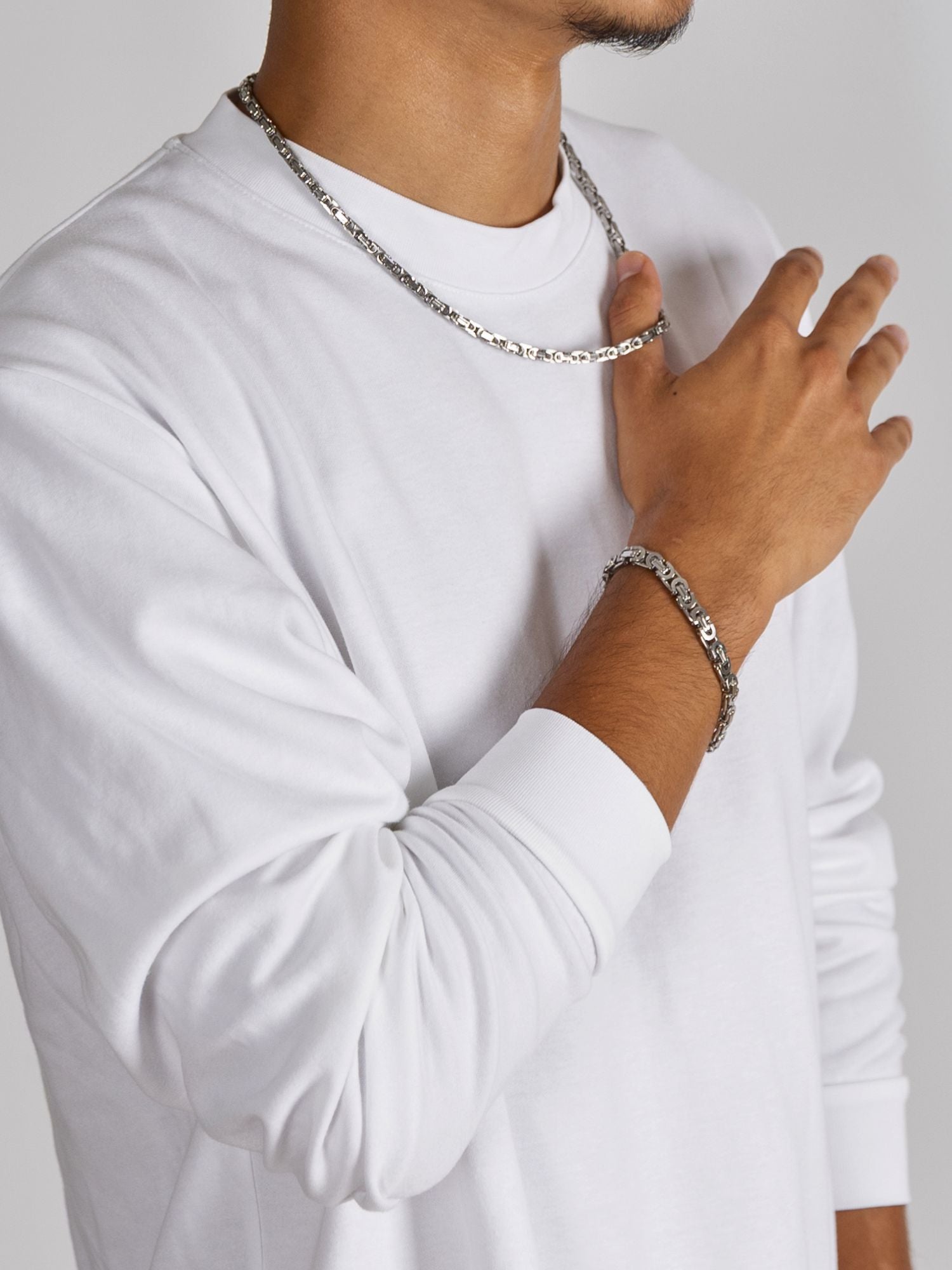 Man wearing a Zilveren Konings Schakel Ketting 5MM and bracelet, showcasing stylish silver jewelry.