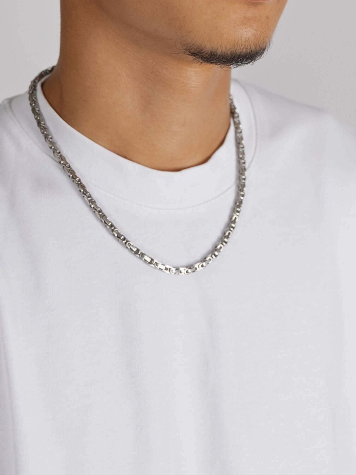 Zilveren Konings Schakel Ketting 5MM dichtbij gedragen op een witte t-shirt, elegant en stoer accessoire.